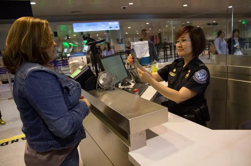 CBP officer reviewing travel documents at a port of entry, representing compliance checks and operational execution.